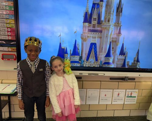  Two students posing in front of a castle for fairytale project.