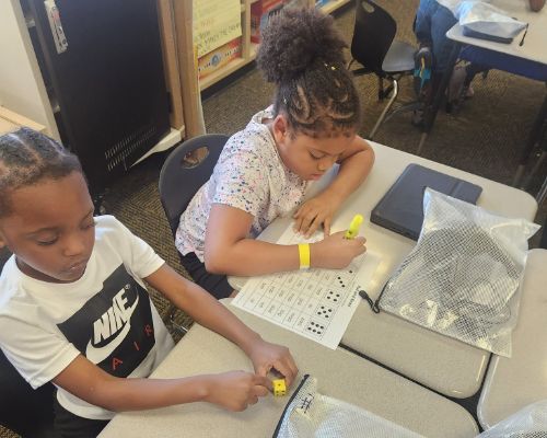  Two students rolling dice and finding words on the paper