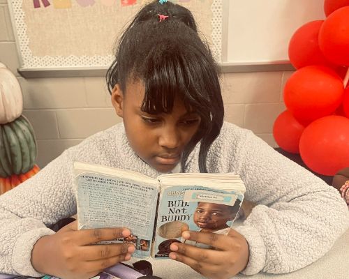  Student reading a book while waiting on the bus