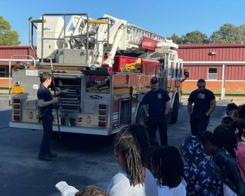  Students with firefighters looking at fire truck