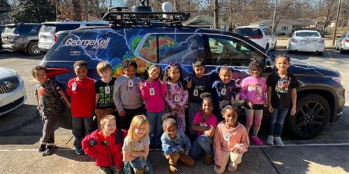 Students next to storm tracker vehicle. 