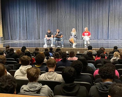  Four alumni members on the PAC stage speak to JHS seniors.