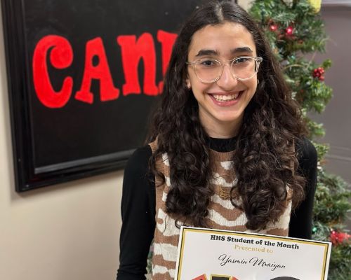  Yasmin smiles holding her student of the month certificate
