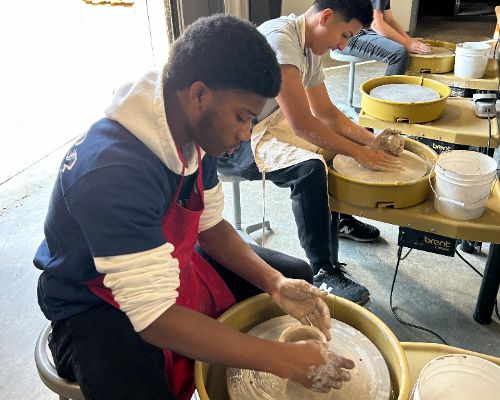  Student works clay on pottery wheel